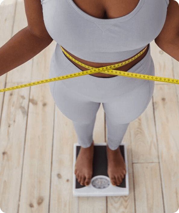 Woman measuring her waist while standing on a scale