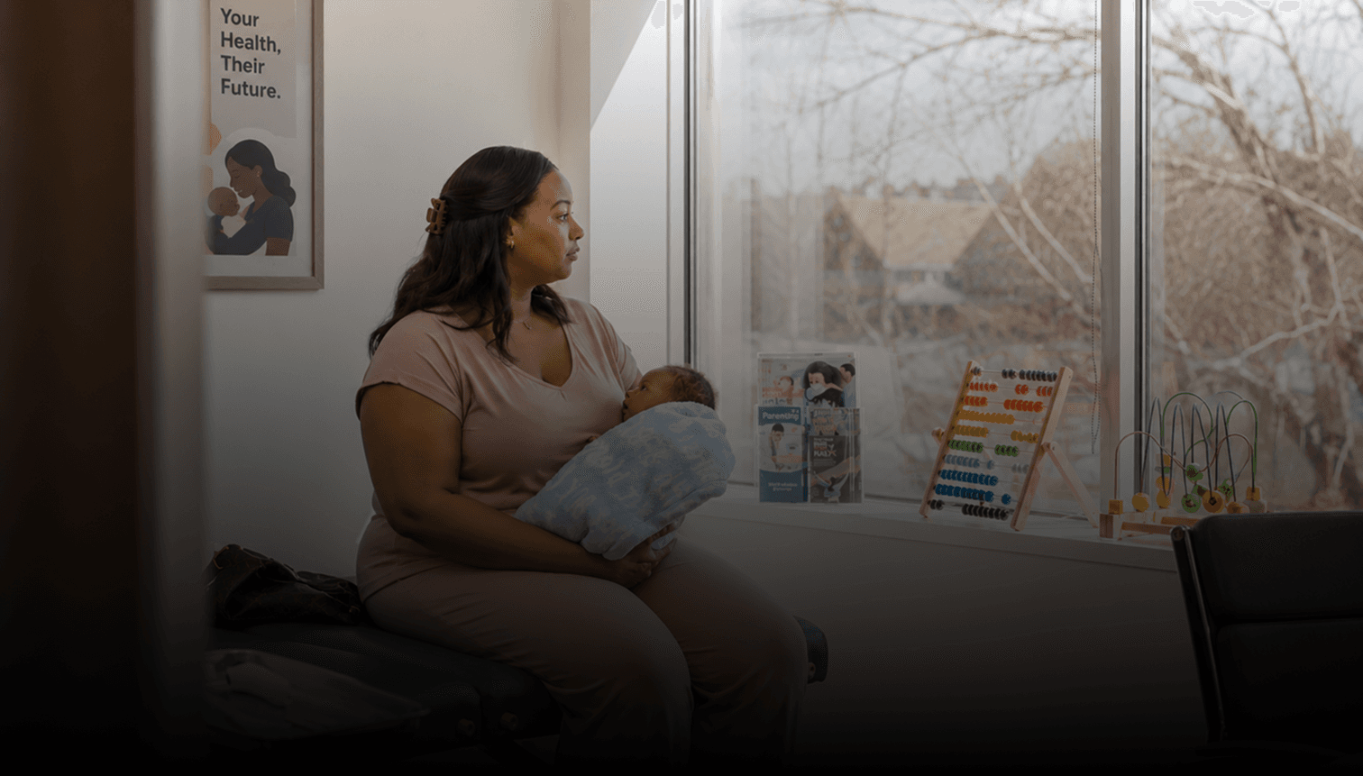 Woman sitting by a window holding a baby